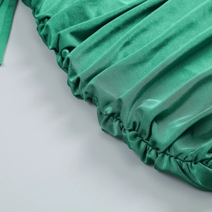 Dettaglio macro del tessuto plissettato verde smeraldo con un sottile riflesso satinato