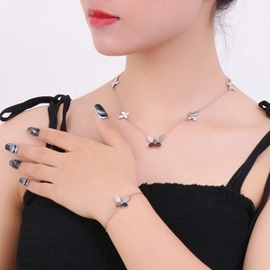 Close-up of a silver butterfly necklace and bracelet set worn by a female model
