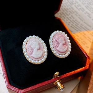 Detail of vintage cameo pearl earrings with pink base and gold metal in a red jewelry box