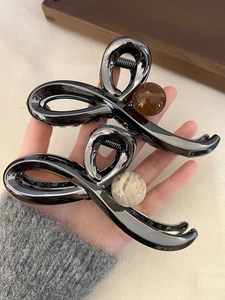 Macro detail of dark grey metallic butterfly hair clips with amber and marble beads