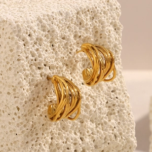 Dettaglio degli orecchini a forma di C placcati oro 18K su superficie in pietra bianca