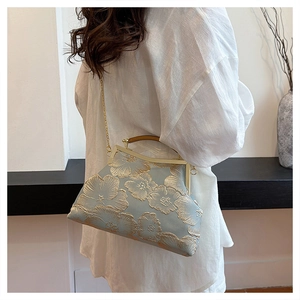 Close-up of floral embroidery detail on vintage blue satin handbag with gold frame