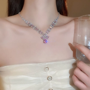 Close-up of sparkling silver necklace featuring square pink zircons and a water drop pendant