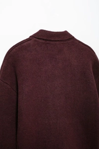 Gros plan détaillé du pull en maille bordeaux montrant la texture et le col à revers