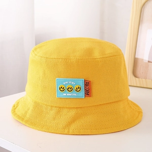 Dettaglio cappello alla pescatora giallo in cotone con patch smile e etichetta