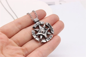 Détail d'un pendentif boussole en acier vintage tenu en main pour la taille et texture
