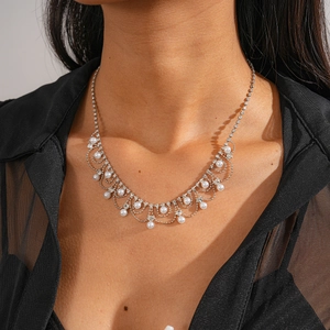 Gros plan du collier avec strass et perles fantaisie sur un haut en maille noire