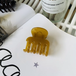 Close-up of translucent amber hair claw clip on a book page with natural lighting