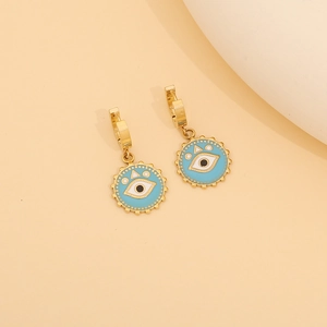 Detail of gold evil eye earrings with blue enamel and beaded metal edges on beige