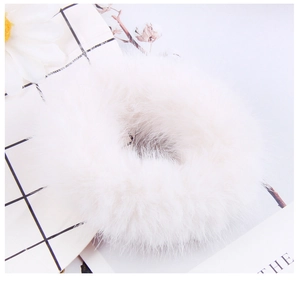 Close-up of white plush hair scrunchie with soft faux fur texture and daisy background