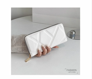 Detail of cream white PU leather long wallet with geometric quilted pattern and gold zipper
