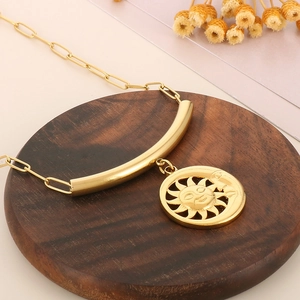 Détail du pendentif soleil et lune en or sur chaîne trombones sur socle en bois