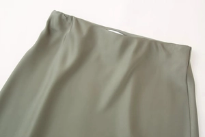 Detailed macro shot of the satin midi skirt waist showing soft green silk fabric texture