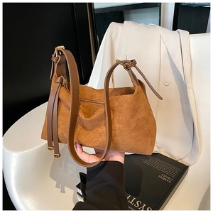 Detail view of brown suede shoulder bag with adjustable strap and golden metal buckle
