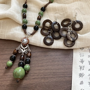 Detailed view of ethnic necklace and earrings set with wooden beads and green tassels
