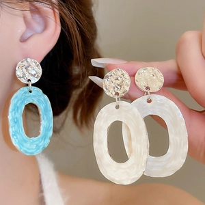 Detailed close-up of textured oval hoop earrings with ripple finish and blue enamel inlay
