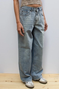 Detail view showing the loose fit and soft drape of light blue wide leg denim jeans on model