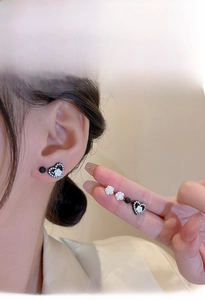 Detail showing elegant black heart zircon studs and white rose earrings set on ear
