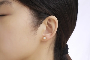 Close-up of minimalist gold-plated earrings with white pearl detail on a female model