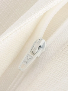 Macro view of a white plastic zipper head and woven fabric texture on a two-piece suit