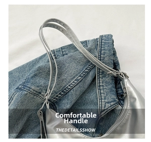 Close-up of metallic silver handbag with zipper closure on blue denim jacket