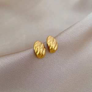 Minimalist gold titanium steel twisted egg-shaped stud earrings on champagne silk fabric