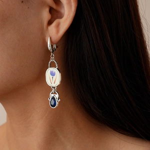 Détail de boucles d'oreilles vintage avec motif tulipe et pierre bleue en goutte
