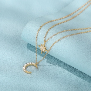 Detailed close-up of double-layered gold necklace with crystal star and moon pendants