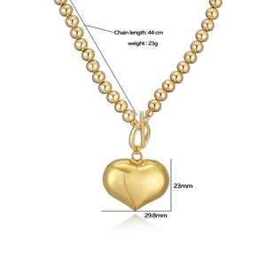 Golden heart pendant necklace with beaded chain and OT buckle on white background