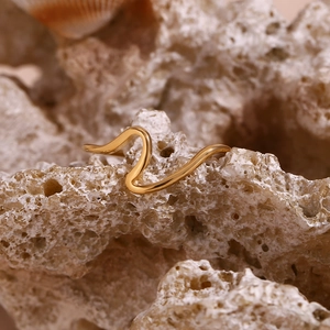 Detail of 18K gold plated stainless steel wave ring on natural coral stone background