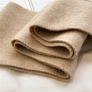 Close-up of thick knitted beige wool fabric texture showing warm and soft material