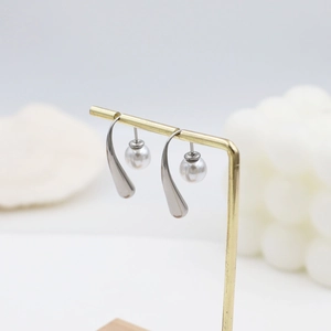 Detailed view of silver water drop earrings with pearls on a golden display stand