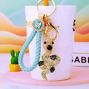 Detail of snake rhinestone keychain with blue braided lanyard and lucky coin pendant