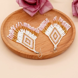 Böhmische Quastenohrringe mit rosa und goldenem Rautenmuster auf Holztablett