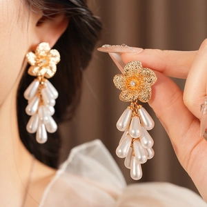 Détails des boucles d'oreilles fleurs dorées avec perles et pompons style vintage