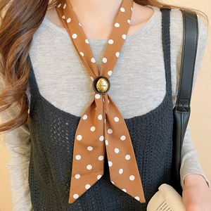 Close-up of brown polka dot silk scarf necklace with a gold-rimmed round metal buckle