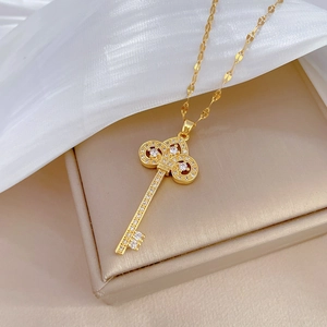Close-up of golden crown key necklace with sparkling rhinestones on silk background