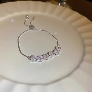 Adjustable silver bracelet with six sparkling round zircons displayed on a ceramic dish