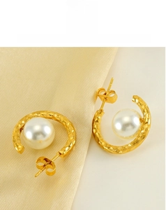 Detailed view of C-shaped hammered gold earrings with elegant white pearl accents
