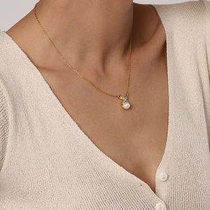 Nahaufnahme der minimalistischen Goldkette mit weißer Perle und Zirkon am Modell