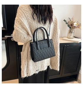 Close-up of black quilted tote bag with diamond stitching and adjustable strap