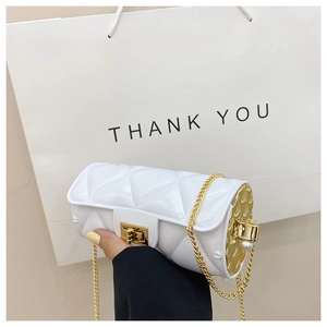 Detailed view of white quilted cylinder bag with gold chain and pearl embellishments