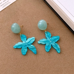 Macro shot of starfish resin pendant earrings with glitter details and seafoam green beads