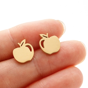 Macro detail of gold apple studs with brushed metal texture on a finger