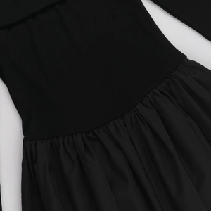 Macro shot of black off-shoulder dress featuring ribbed knit and woven pleated stitching