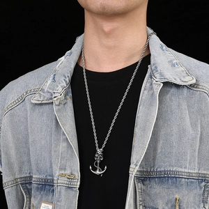 Close-up of anchor and skull pendant with rope chain on model in denim jacket