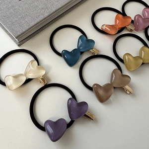 Flat lay of colorful heart-shaped resin hair clips and elastic ties in pastel colors