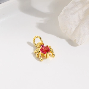 Detailed macro view of a gold spider charm featuring a red heart-shaped gemstone center