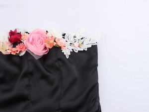 Nahaufnahme der rosa und roten 3D-Blumen mit weißer Spitze an einem schwarzen Satin-Oberteil