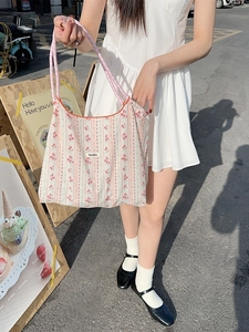 Floral canvas tote bag with pink checkered handles and Sozakka label in outdoor street view